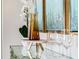 Decorative glass console table adorned with flowers, glassware, and gold-framed art at 3805 Royal Azalea Way, Sanford, FL 32773