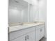 Bright bathroom featuring dual sinks with white cabinetry and large mirrors, illuminated by modern lighting at 4709 Jasmine Cir, Leesburg, FL 34748