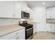 Bright kitchen features white cabinets, stainless steel appliances, and light countertops at 4709 Jasmine Cir, Leesburg, FL 34748