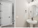 Bathroom featuring a pedestal sink, modern fixtures, and a door with stairs in the background at 5133 Passion Flower Way, Winter Garden, FL 34787