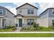 Charming two-story home featuring a covered front porch, landscaped yard, and a light gray exterior at 5133 Passion Flower Way, Winter Garden, FL 34787