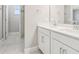 Bright bathroom featuring double sink vanity with white cabinets and a tiled shower with glass door at 5217 Passion Flower Way, Winter Garden, FL 34787