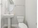 Clean half bath featuring a pedestal sink, toilet, and a round mirror at 5217 Passion Flower Way, Winter Garden, FL 34787