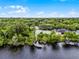 Aerial view of tennis court, lake and private dock surrounded by lush trees and beautiful landscaping at 889 Kensington Gardens Ct, Oviedo, FL 32765