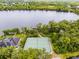 Aerial view of tennis court, lake and private dock surrounded by lush trees and mature landscaping at 889 Kensington Gardens Ct, Oviedo, FL 32765