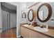 Bathroom featuring double sinks, framed oval mirrors, and wood floors at 889 Kensington Gardens Ct, Oviedo, FL 32765