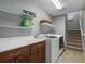 Well-lit laundry room with front loading washer and dryer, cabinets, shelves and stairs to another level at 889 Kensington Gardens Ct, Oviedo, FL 32765
