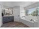 Bright bathroom with a soaking tub, vanity, and views of the greenery outside at 10033 Hart Branch Cir, Orlando, FL 32832