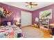 This bedroom features purple walls, a colorful quilt, a ceiling fan, and a built-in bookshelf at 109 Romney Marsh Rd, Longwood, FL 32779