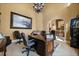 Home office with an ornate wooden desk, leather chairs, and a cityscape painting, providing a professional workspace at 1112 Orange Ave, Winter Springs, FL 32708