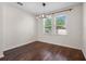 Minimalist bedroom design with hardwood floors, two windows providing natural light, and a modern light fixture at 12188 Ryegrass Trl, Orlando, FL 32824