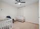 Cozy bedroom with white cribs, a ceiling fan, and a comfortable chair at 12188 Ryegrass Trl, Orlando, FL 32824