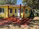 Home exterior featuring a red painted porch, colorful yellow walls, and green landscaping at 1236 Illinois St, Orlando, FL 32803