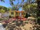 Charming yellow home featuring a cozy front porch, stone walkway, and lush, mature trees at 1236 Illinois St, Orlando, FL 32803