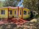 Inviting yellow home with a cozy front porch, surrounded by lush greenery and a stone walkway at 1236 Illinois St, Orlando, FL 32803