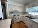 Clean kitchen featuring white cabinets, backsplash, stainless steel sink, and hardwood floors at 1236 Illinois St, Orlando, FL 32803