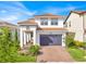 Charming two-story home featuring a tile roof, brick driveway, manicured landscaping, and a covered front entrance at 13543 Abberwick Dr, Orlando, FL 32832