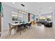 Open-concept living and dining area with modern lighting, large windows, and a sleek dining table with chairs at 13543 Abberwick Dr, Orlando, FL 32832