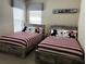 Cozy bedroom with two beds featuring themed bedding, coordinated decor, and ample natural light from the windows at 1449 Fairview Cir, Reunion, FL 34747