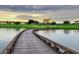 Scenic view of a golf course with a wooden bridge over a lake, and a luxurious hotel in the distance at 1449 Fairview Cir, Reunion, FL 34747