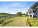 Spacious backyard featuring lush grass, a black metal fence, and serene lake views at 14749 Walcott Ave, Orlando, FL 32827