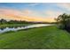 Picturesque view of the serene lake with clear skies, beautiful landscaping, and lush green grass at 14749 Walcott Ave, Orlando, FL 32827
