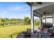 Relaxing covered patio features comfortable seating with a serene view of the backyard, lake, and landscaped lawn at 14749 Walcott Ave, Orlando, FL 32827