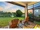 Relaxing covered patio featuring comfortable Adirondack chairs with views of the serene lake and manicured lawn at 14749 Walcott Ave, Orlando, FL 32827