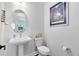 Modern powder room with pedestal sink, elongated toilet, and decorative artwork for an elegant touch at 14749 Walcott Ave, Orlando, FL 32827