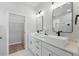 Bright bathroom with double sinks, sleek fixtures, modern mirrors, and a view of walk-in closet at 1620 Haddock St, St Cloud, FL 34771