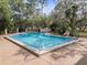 Community swimming pool with clear blue water, surrounded by concrete deck, fencing and lounging furniture at 1631 Oak Hill Trl, Kissimmee, FL 34747