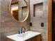 Stylish bathroom features a modern vanity, round mirror, and beautiful wood-look accent wall at 2114 Bluff Oak St, Apopka, FL 32712