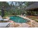 Screened-in pool area with a waterfall, surrounded by stone pavers and lounge chairs at 2114 Bluff Oak St, Apopka, FL 32712