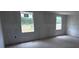 A bedroom with drywall installed, two windows providing natural light, and unfinished floors, awaiting personalization at 22117 Amberbush Court, Mount Dora, FL 32757