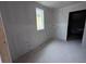 A room with drywall installed, a window providing natural light, and unfinished floors, awaiting personalization at 22117 Amberbush Court, Mount Dora, FL 32757