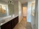 A bathroom features a double sink vanity with dark wood cabinets and tile flooring at 2620 Blowing Breeze Ave, Kissimmee, FL 34744