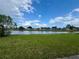 Expansive backyard with serene lake view behind a chain-link fence, under a blue, partly cloudy sky at 2673 Dixie Ln, Kissimmee, FL 34744