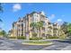 Multi-story tan condo building with balconies, palm trees, parking and blue skies at 2781 Almaton Loop # 105, Kissimmee, FL 34747