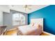 Bright bedroom features a large window, hardwood floors, and blue accent wall at 300 E South St # 6003, Orlando, FL 32801