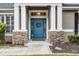Close-up of a stylish blue front door framed by stone pillars and a welcoming wreath at 413 Macchi Ave, Oakland, FL 34787