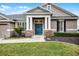 Inviting home exterior with a blue front door, stone columns, and lush green lawn at 413 Macchi Ave, Oakland, FL 34787