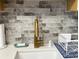 Close up of kitchen sink featuring modern gold faucet and decorative tile backsplash at 567 E Orange St # 567, Altamonte Springs, FL 32701