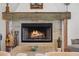 Close-up of a brick fireplace with a decorative wood mantel, firewood, and warm flames burning inside at 645 Manor Rd, Maitland, FL 32751
