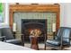 Close up of tiled fireplace with wooden mantle and chairs on either side at 645 Manor Rd, Maitland, FL 32751