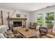 Cozy living room features a brick fireplace with decorative mantel, wood floors and two large picture windows at 645 Manor Rd, Maitland, FL 32751