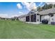 Expansive backyard with lush green lawn and view of the screened patio and surrounding houses at 682 Lexington Dr, Clermont, FL 34711