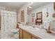 Well-lit bathroom featuring a shower with a floral curtain, toilet, and vanity with a mirror at 682 Lexington Dr, Clermont, FL 34711