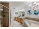 Bathroom featuring double sinks, walk-in shower, tub, and floral artwork at 7420 Cypress Grove Rd # 132, Orlando, FL 32819