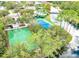 This aerial view highlights the community amenities, featuring a basketball court, tennis court, pool, and scenic pond with a bridge at 9126 Shadowbrook Trl, Orlando, FL 32825