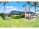 Green backyard with manicured hedges, palm trees and a screened-in pool at 9126 Shadowbrook Trl, Orlando, FL 32825